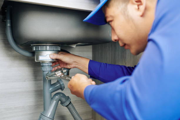 serious plumber using wrench when repairing leaky drain in kitchen